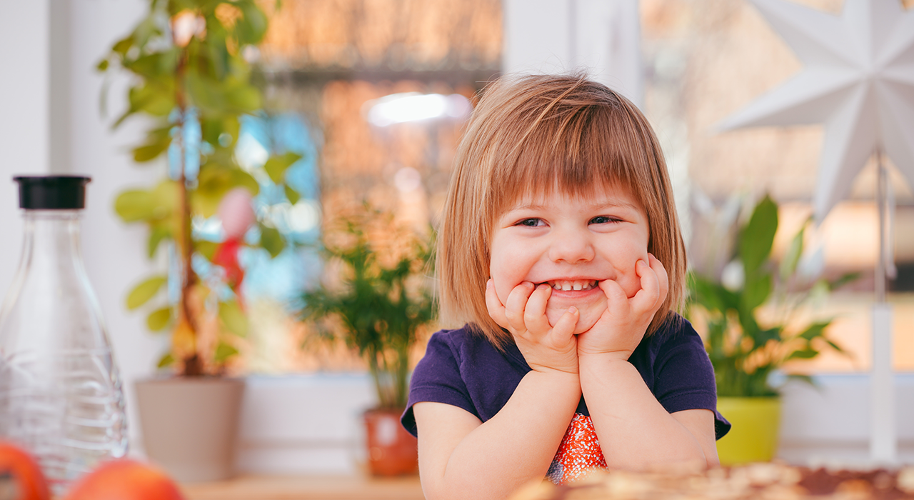 Child smiling with hands on cheeks